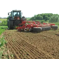 Traktor z agregatem uprawowym wykonuje podorywkę na polu.