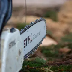 Zbliżenie na łańcuch piły Stihl, z kroplami wody. Różne rodzaje łańcuchów do piły są kluczowe dla efektywnego cięcia.