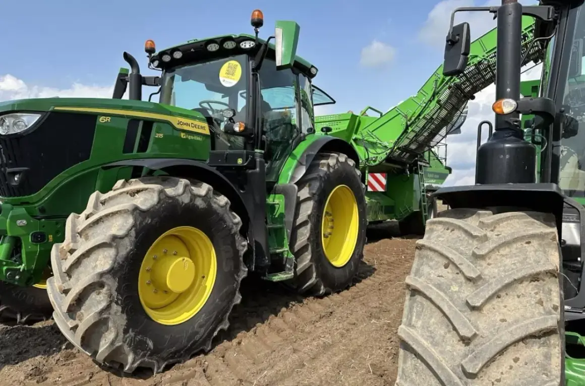 Zielony traktor John Deere z przyczepą do zbioru ziemniaków. Wśród wielu marek traktorów, John Deere wyróżnia się mocą i niezawodnością.